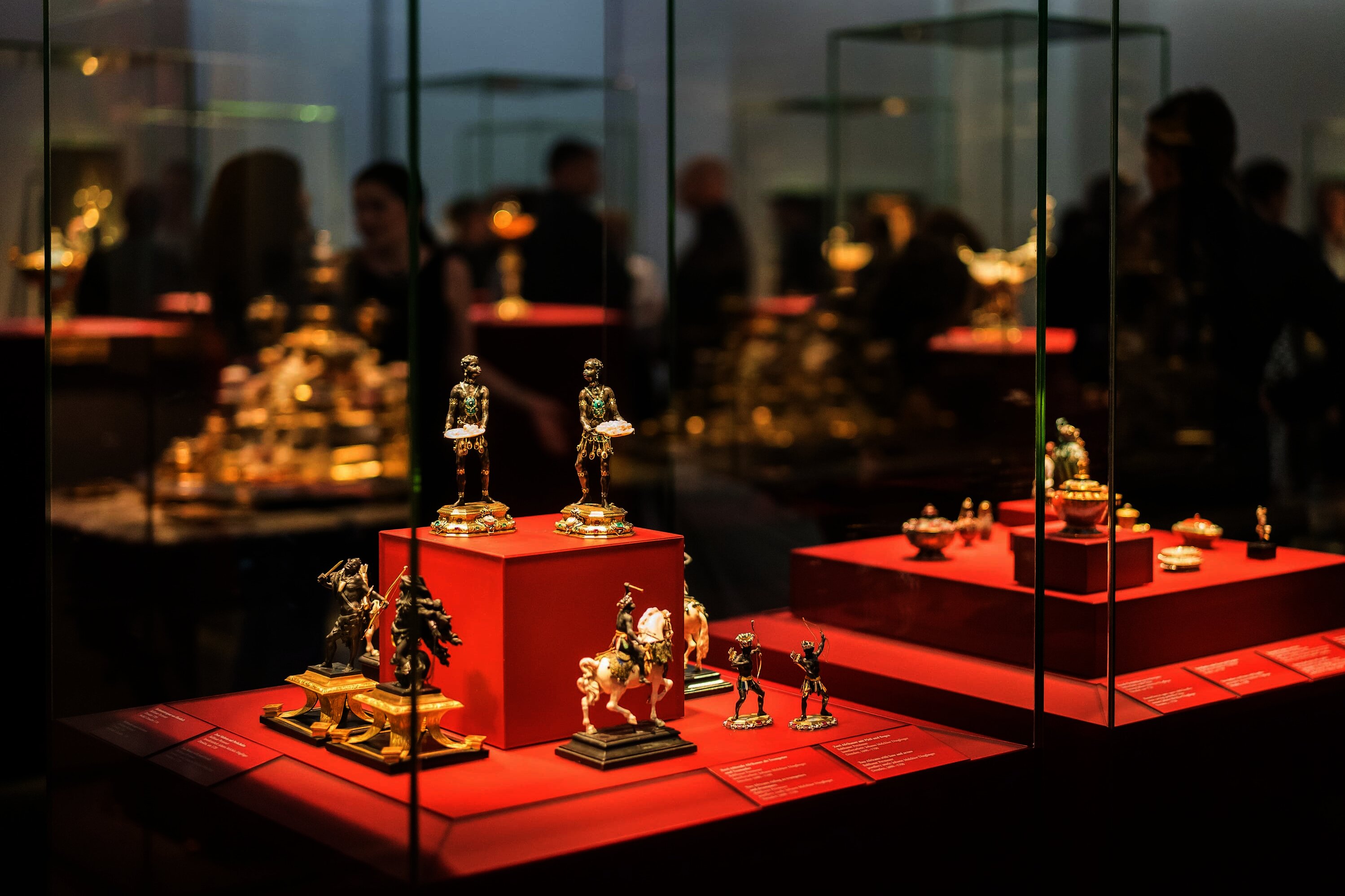 Im Vordergrund sind Ausstellungsstücke in Vitrinen zu sehen, im Hintergrund eine Menschenansammlung